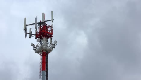red-and-white-telecommunication-antenna-tower-with-signal-repeater,-cloudy-sky,-4k-timelapse