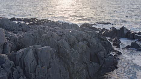 Rocky-cape-with-sun-reflected-ocean-at-sunset-golden-hour