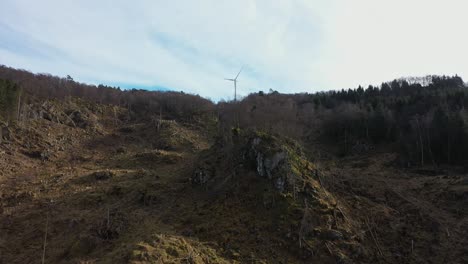 Flying-up-hillside-against-rotating-wind-turbine-in-Midtfjellet-wind-park---One-single-turbine-producing-electricity-along-coast-of-Norway