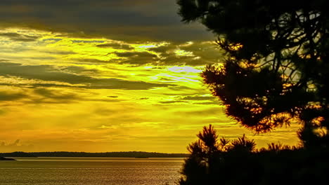 Sunset-over-the-lake-near-the-shore-in-timelapse-with-dark-clouds-movement-over-yellow-sky