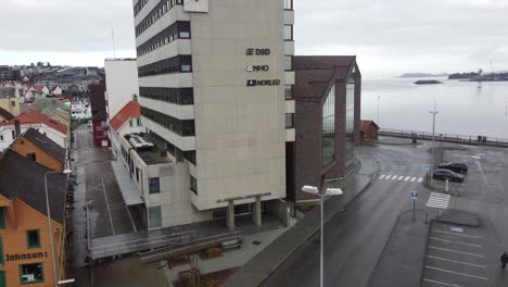 Edificio-De-Oficinas-Principal-De-Norled-Y-Nho-En-Stavanger-Con-La-Ciudad-Y-El-Fiordo-En-El-Fondo---Norled-Es-Una-De-Las-Compañías-De-Transporte-Y-Transbordadores-Más-Grandes-De-Noruega---Antena-En-Movimiento-Hacia-Arriba