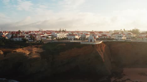 Toma-Aérea-De-Una-Ciudad-Al-Atardecer-A-Lo-Largo-De-Los-Acantilados-Costeros-Del-Oeste-En-Portugal