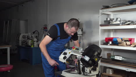 Male-worker-preparing-an-electric-saw-machine-for-cutting,-workshop