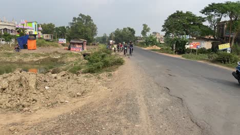 Grupo-De-Ciclistas-Que-Viajan-Por-Un-Camino-Rural-En-India