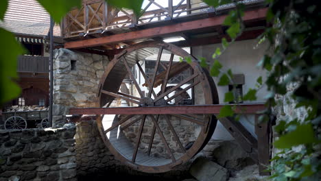 Old-watermill-wheel-on-display-in-a-renovated-antique-cottage-with-ivy