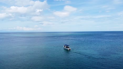 Aerial-drone-flying-over-a-moving-dive-boat-on-stunning-coral-reef-ocean-at-tropical-island-getaway-destination-of-Atauro-Island,-Timor-Leste