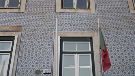 Portuguese-droop-flag-by-window-on-typical-picturesque-tiled-facade-building-in-Lisbon