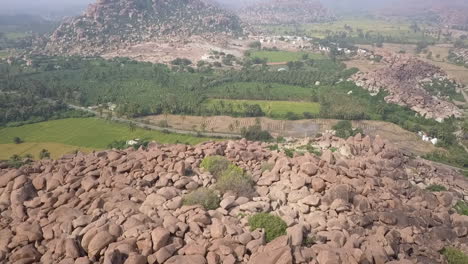 Aerial-descends-to-mountain-of-giant-stone-boulders-in-Hampi,-India