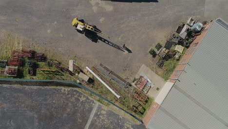 Aerial-perspective-of-a-old-yellow-crane-moving-a-heavy-metal-bar-with-help-from-factory-worker-moving-the-product-specifically-into-place