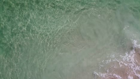 Luftaufnahme-über-Wellen,-Die-Auf-Den-Strand-Und-Türkisfarbenes-Meerwasser-Krachen