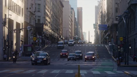 Low-angle-establishing-shot-capturing-the-lifestyle-in-Buenos-Aires-city-with-downtown-traffic-motions-and-pedestrians-crossing-at-the-intersection-of-Leandro-N-Alem-and-Corrientes-avenue