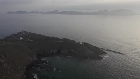 Vista-Panorámica-Del-Faro-De-Cabo-Home-En-La-Costa-De-Galicia-En-España,-Parque-Nacional-De-Las-Islas-Cies-En-El-Fondo---Toma-Aérea-De-Drones