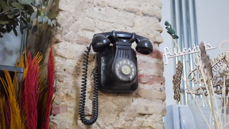 Altes-Telefon-Mit-Wählscheibe,-Das-An-Einer-Ziegelwand-In-Einem-Geschäft-Hängt
