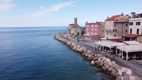 Piran,-Istria,-Slovenia---Boulevard-with-Walking-Touristst,-Restaurants-and-Church