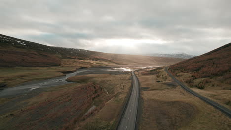 Aerial-flyover-above-Iceland-highway-illuminated-by-sun-beams-in-beautiful-river-valley