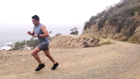 A-static-shot-of-a-man-running-up-a-dirt-hill-by-the-beach