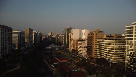 AERIAL---Luxury-buildings-and-tennis-courts,-Costa-Verde,-Lima,-Peru,-truck-right