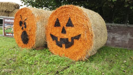 Round-rolled-hay-bale-painted-Halloween-pumpkin-funny-faces-farmland-advertising