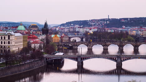 Prague-nightfall-timelapse,-turning-on-street-lamps-over-famous-bridges,-zoom-out-view