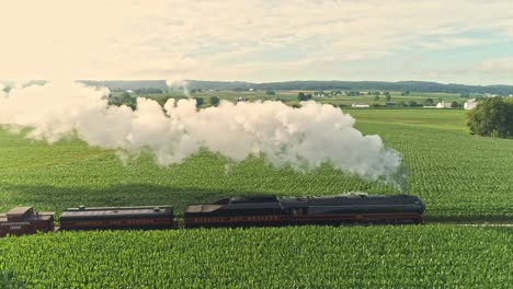 Aerial-View-of-an-Antique-Steam-Engine-and-Passenger-Coaches-Traveling-Along-Countryside-Blowing-Smoke-and-Drone-Traveling-Parallel-and-Close-To-It,-on-a-Sunny-Summer-Day