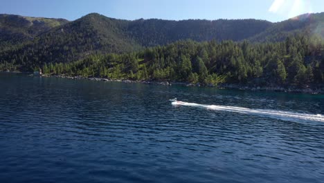 Speedboat-Sailing-And-Leaving-Wake-In-The-Water-With-Lush-Green-Forest-And-Mountains