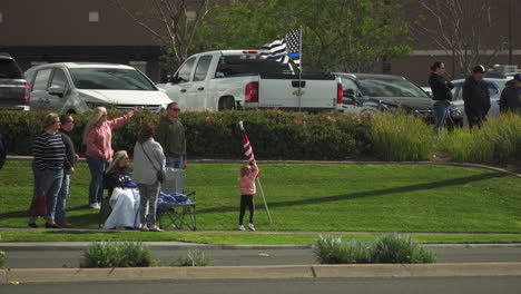 A-family-waves-an-American-flag-as-a-funeral-procession-drives-by