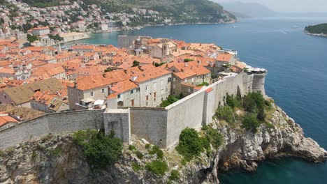 Luftdrohnenaufnahme-über-Der-Alten-Festungsmauer-Entlang-Der-Altstadt-Von-Dubrovnik,-Kroatien,-Mit-Blick-Auf-Gebäudedächer-An-Einem-Sonnigen-Tag