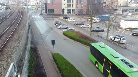 Green-colored-kolumbus-bus-is-driving-through-street-approaching-bus-terminal-in-Sandnes-southern-Norway