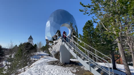 Static-shot-of-a-Tourist-standing-in-the-middel-of-the-Eye-of-the-North-in-Svolvaer-Park-with-blue-Sky-and-snow