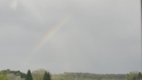 Rainbow-appearing-in-sky-over-neighborhood-after-storm-in-afternoon,-Germany,-Europe