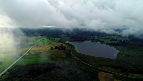 Rückwärtsbewegte-Luftaufnahme-Der-Wunderschönen-Ländlichen-Landschaft-Mit-Grünen-Wiesen-Und-Kleinen-Seen,-Die-Tagsüber-An-Einem-Bewölkten-Tag-Sichtbar-Sind