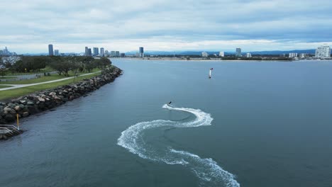 A-jet-board-carves-through-the-glassy-waters-along-a-city-harbor-break-wall