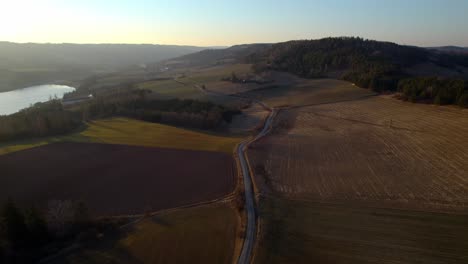 Winding-road-around-the-Křetínka-Letovice-dam,-fields-and-forests-at-golden-and-calm-sunset,-Czech-Republic---aerial-view