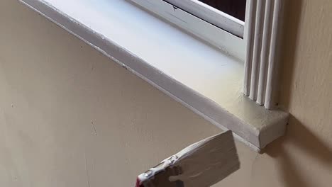 Paint-Brush-Applying-White-Paint-to-Window-Trim,-Open-Window,-Close-Up-on-Brush-and-Hand
