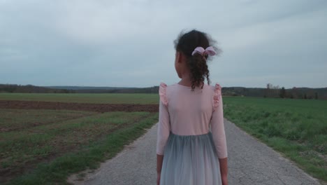 Little-girl-walking-alone-in-thought-on-empty-field-road-at-sunset-in-Schonaich-Germany