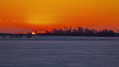 View-of-big-sun-rising-over-the-horizon-during-sunrise-timelapse-during-winter-season-over-white-snow-field