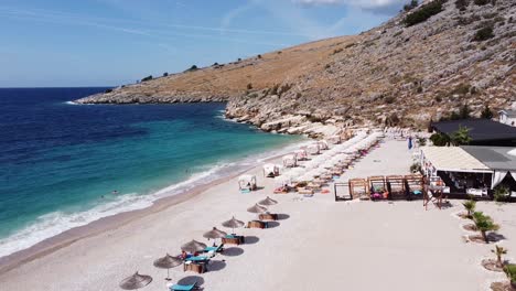Turistas-Nadando-Y-Tomando-El-Sol-En-La-Playa-De-Llamani,-Albania---Antena