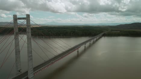 Large-bridge-structure-crossing-a-fast-flowing-river-in-tropics-on-cloudy-day