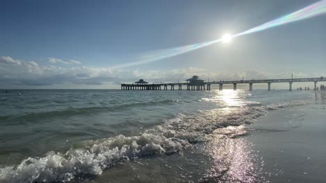 Waves-rolling-at-Fort-Myers-Beach-Pier,-sun-on-a-clearday-at-the-beach