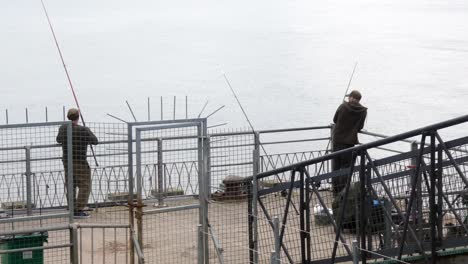 Men-with-fishing-rods-angling-on-Llandudno-pier-jetty-preparing-equipment-and-waiting-in-anticipation