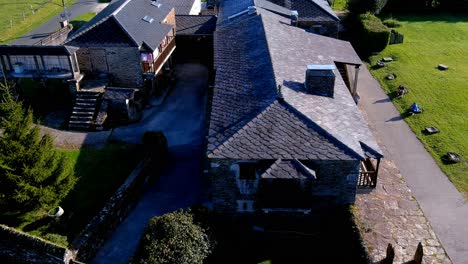 Aerial-drone-backward-moving-shot-over-an-old-house-made-of-stone-walls-been-converted-into-rural-tourist-house-in-ManÃ³n,-Lugo,-Galicia,-Spain