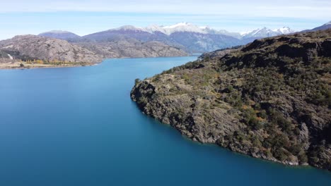 Top-aerial-drone-panoramic-view-Beautiful-snowy-mountains-landscape-and-a-cristal-clear-river-along-gravel-road-Carretera-Austral-in-southern-Patagonia,-Chile
