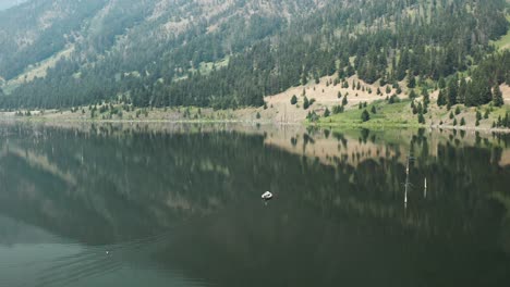 Aerial,-small-motor-boat-sailing-on-Earth-Quake-Lake-in-Montanna