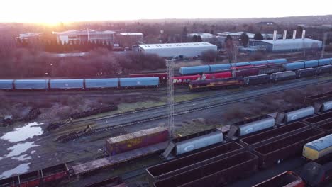 Aerial-view-over-long-train-yard-tracks-and-freight-shipping-tanker-railway-lines-dolly-right-tilt-down-at-sunrise