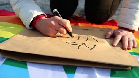 Female-caucasian-hand-writes-anti-war-protest-placard,-slow-motion-close-up-shot