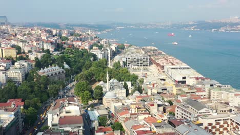 Aerial-view-of-European-buildings-in-Karakoy,-Istanbul-Turkey-on-a-sunny-summer-day-as-boats-cross-the-Bosphorus-River