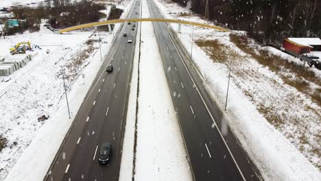 Heavy-snowfall-over-highway-road-in-winter-season,-aerial-descend-view