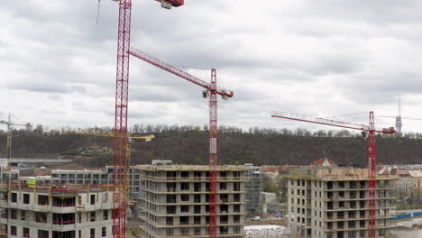 Red-tower-cranes-working-at-construction-site-in-Prague,-cloudy-day