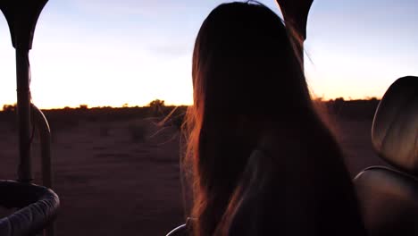 Eine-Morgendliche-Pirschfahrt-Bei-Sonnenaufgang-In-Namibia-–-Eine-Frau-Blickt-Aus-Dem-Safariwagen-In-Die-Wüste