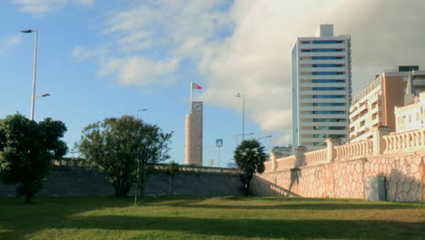 Clock-tower-in-Figueira-da-Foz,-and-the-building-of-the-grand-hotel,-in-the-background-the-blue-sky-with-clouds